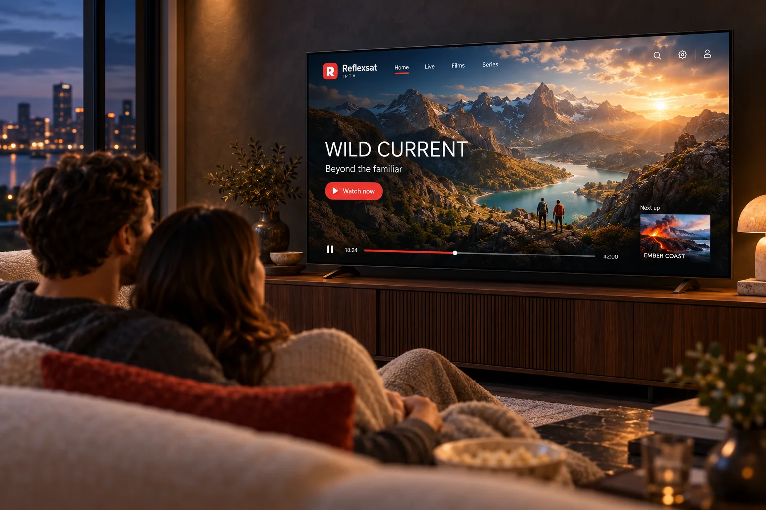 Two adults relaxing on a sofa while a mountain programme plays on the television.